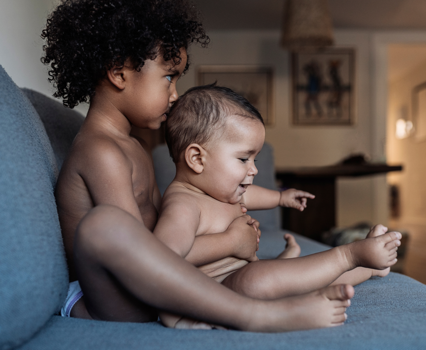 Two young siblings sitting side by side on a couch